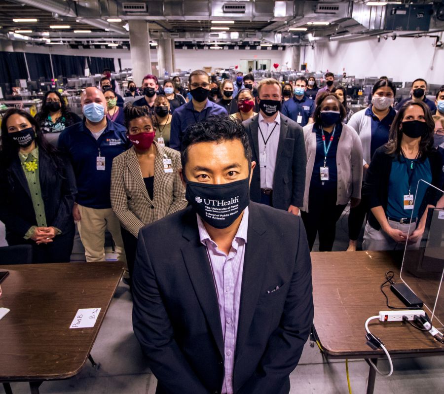 Dr. Tsai wears a mask and stands in front of a group of contact tracers and staff members at the Alamodome contact tracing site.