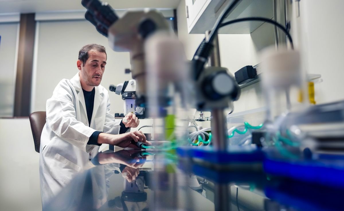 Photo of Victor Lopez del Amo sitting in front of microscope in lab.