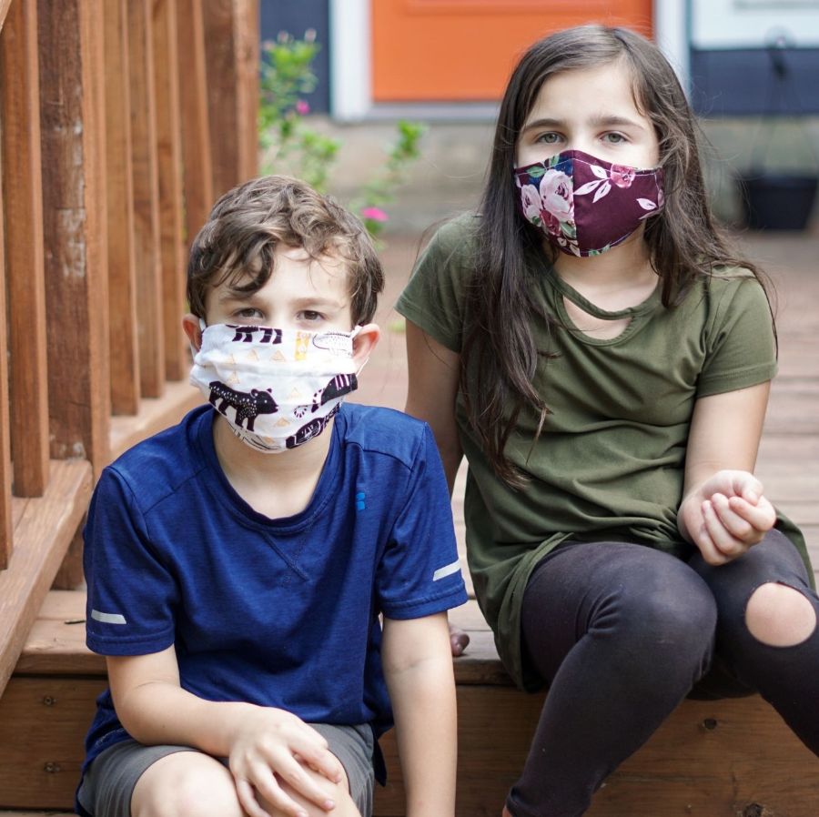 Children wearing masks sit on a staircase