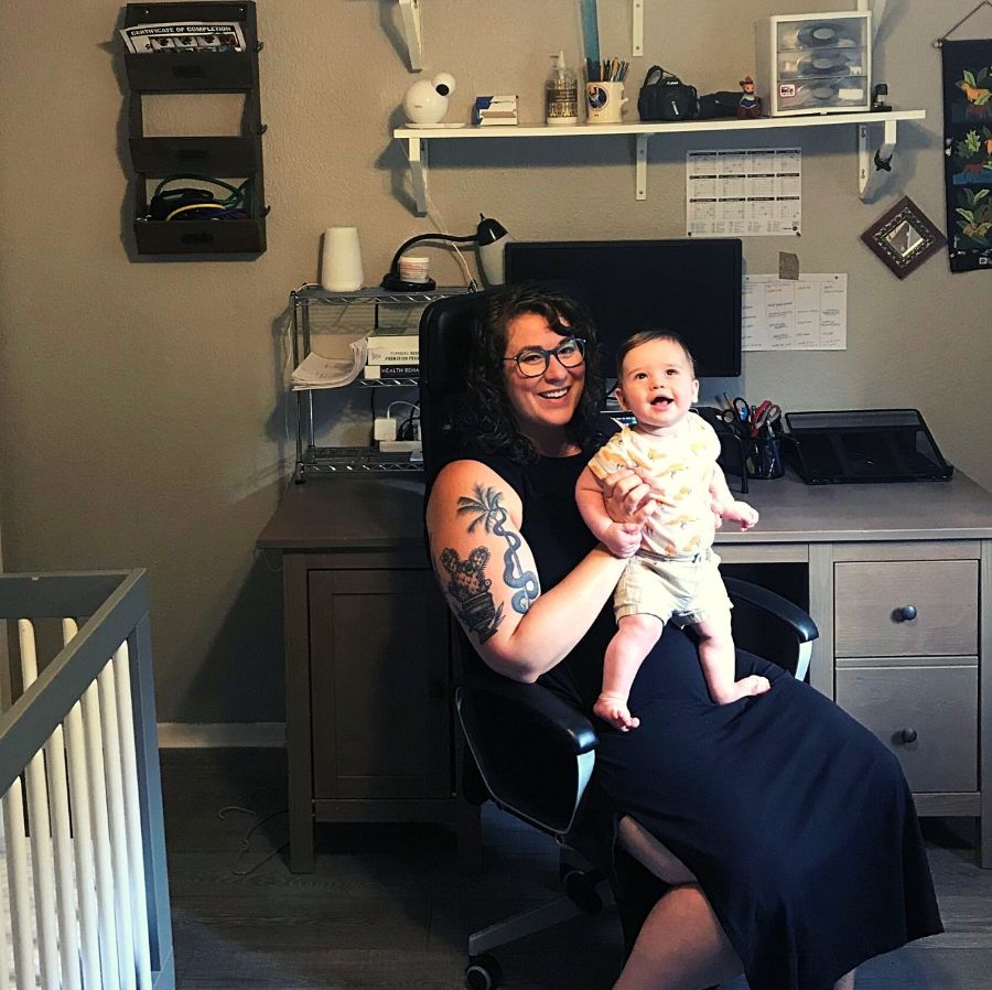 Sierra sits in her home office/nursery, holding her infant son.