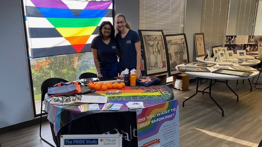 Priya Reddy, MBBS, standing at table with LGBTQIA flag collecting information for survey.