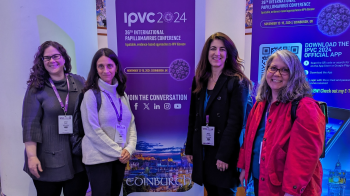 Two women stand on either side of a banner promoting a conference.