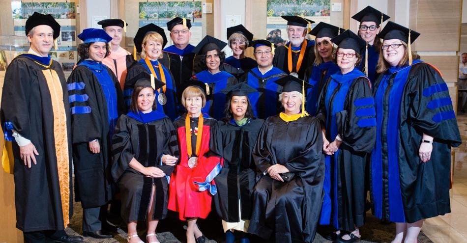 Group of students and  faculty in full graduation regalia.