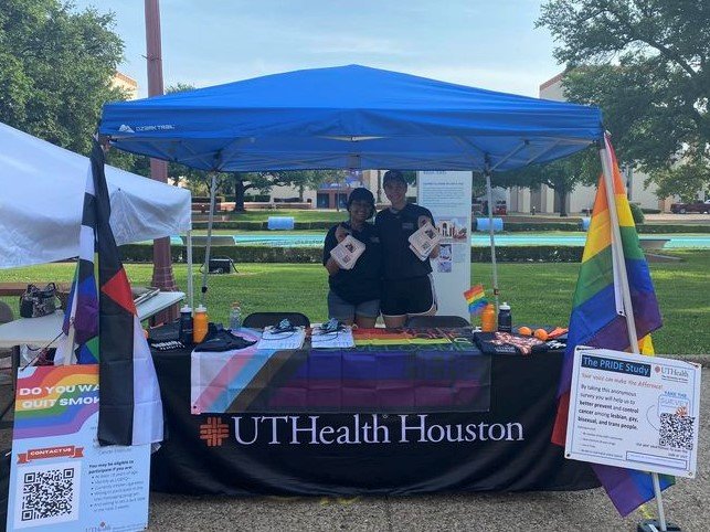 Two UTHealth Houston representatives holding flyers at Houston Pride festival.