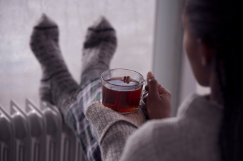 Photo of woman with socks and warm drink trying to warm up. (Photo credit: Getty Images)