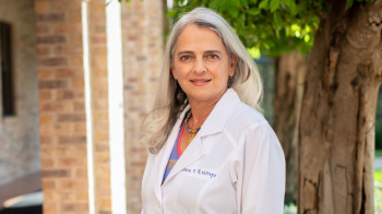 Blanca Restrepo pictured in white coat in front of tree in foreground.