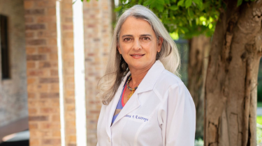 Blanca Restrepo pictured in white coat in front of tree in foreground.