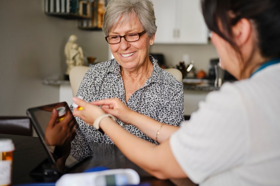 Nurse shows medication to an older woman in her house