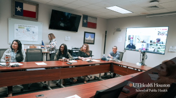 Picture of people sitting at conference table during meeting.
