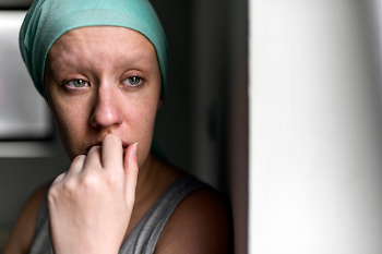 Photo of a grief-stricken woman with cancer looking out the window.