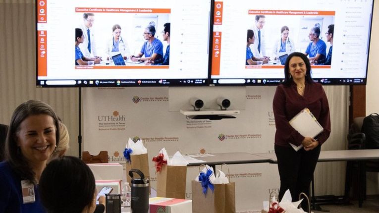Ginger Raya, EdD, MHA, MPA,  (right) smiling in front of a classroom. (Photo by UTHealth Houston)