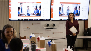 Ginger Raya, EdD, MHA, MPA,  (right) smiling in front of a classroom. (Photo by UTHealth Houston)