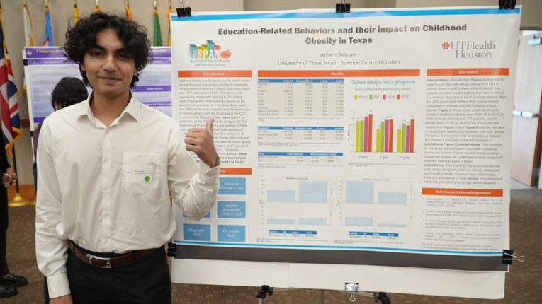 Arham Salman pictured in front of research poster.