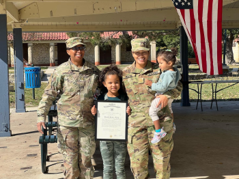 Joanna Moore in uniform with her children holding a certificate at a military exercise event