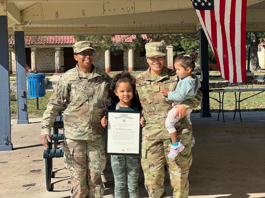 Joanna Moore in uniform with her children holding a certificate at a military exercise event