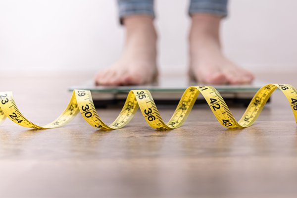 A photograph of a measuring tape in front of a two feet on a scale. Photo by Getty Images