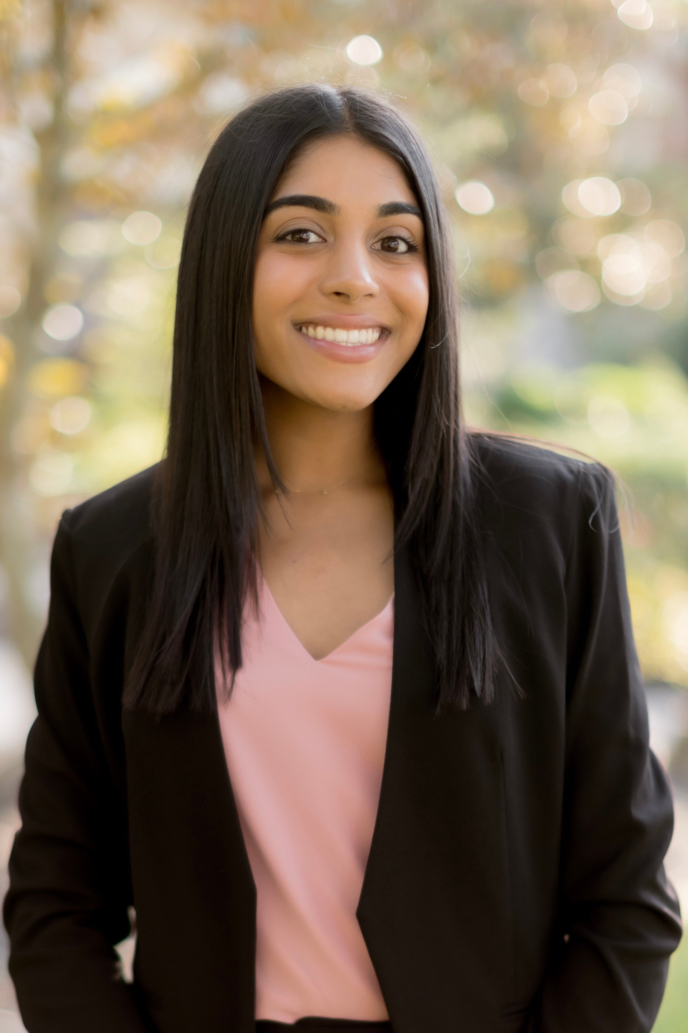 Practicum student Asha Kalapatapu standing in front of green background.