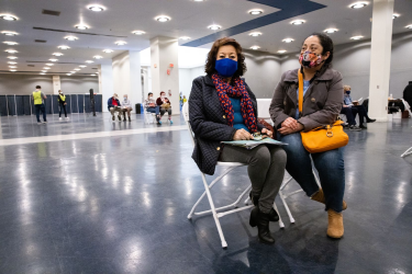 Woman and daughter sit in the post-vaccination waiting area at Fair Park in Dallas.