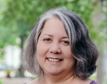 A woman in a purple shirt smiles.