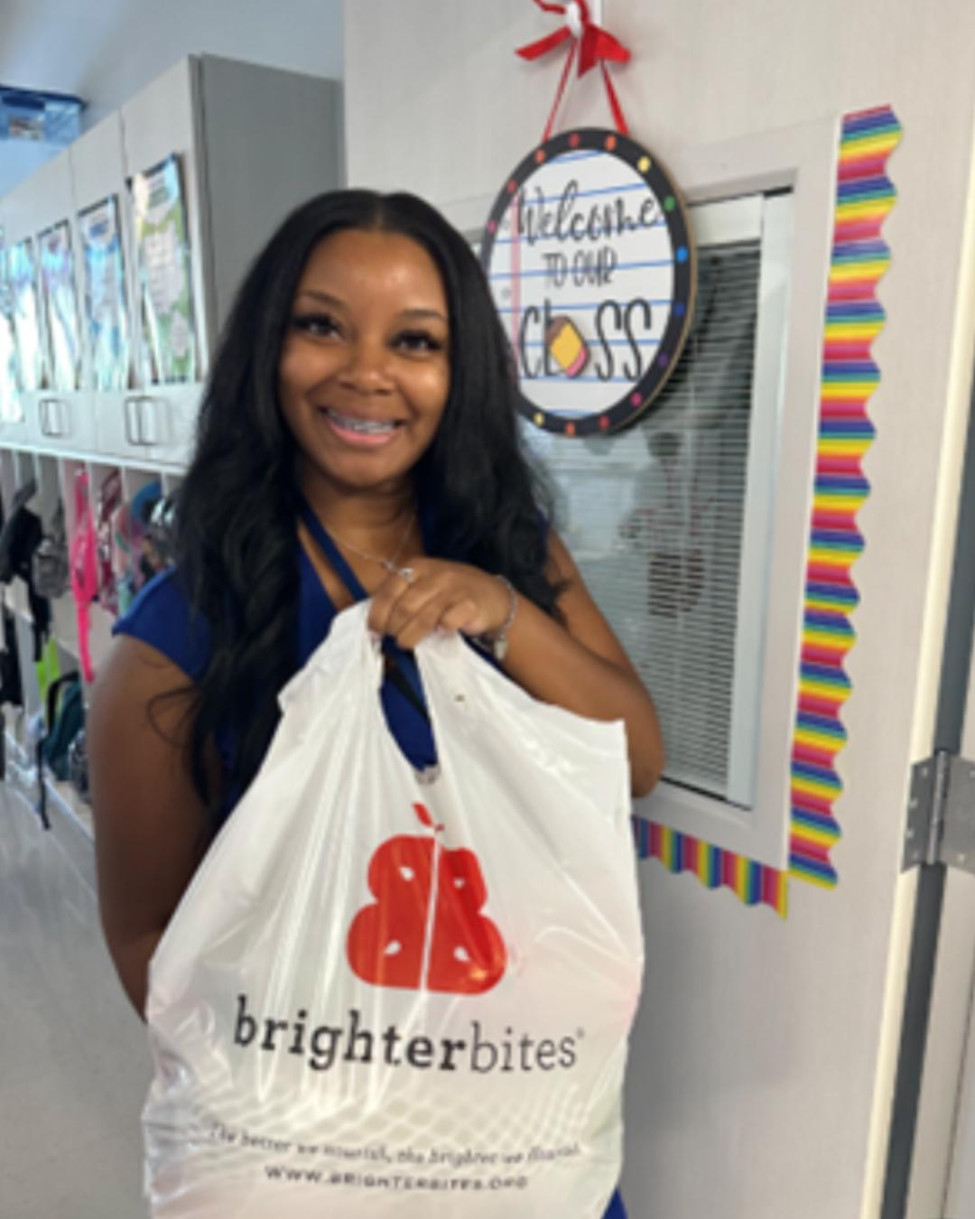 Teacher holding Brighter Bites bag filled with produce.