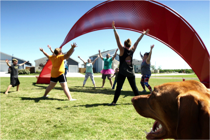 group of people stretching arms up, dog in front right corner