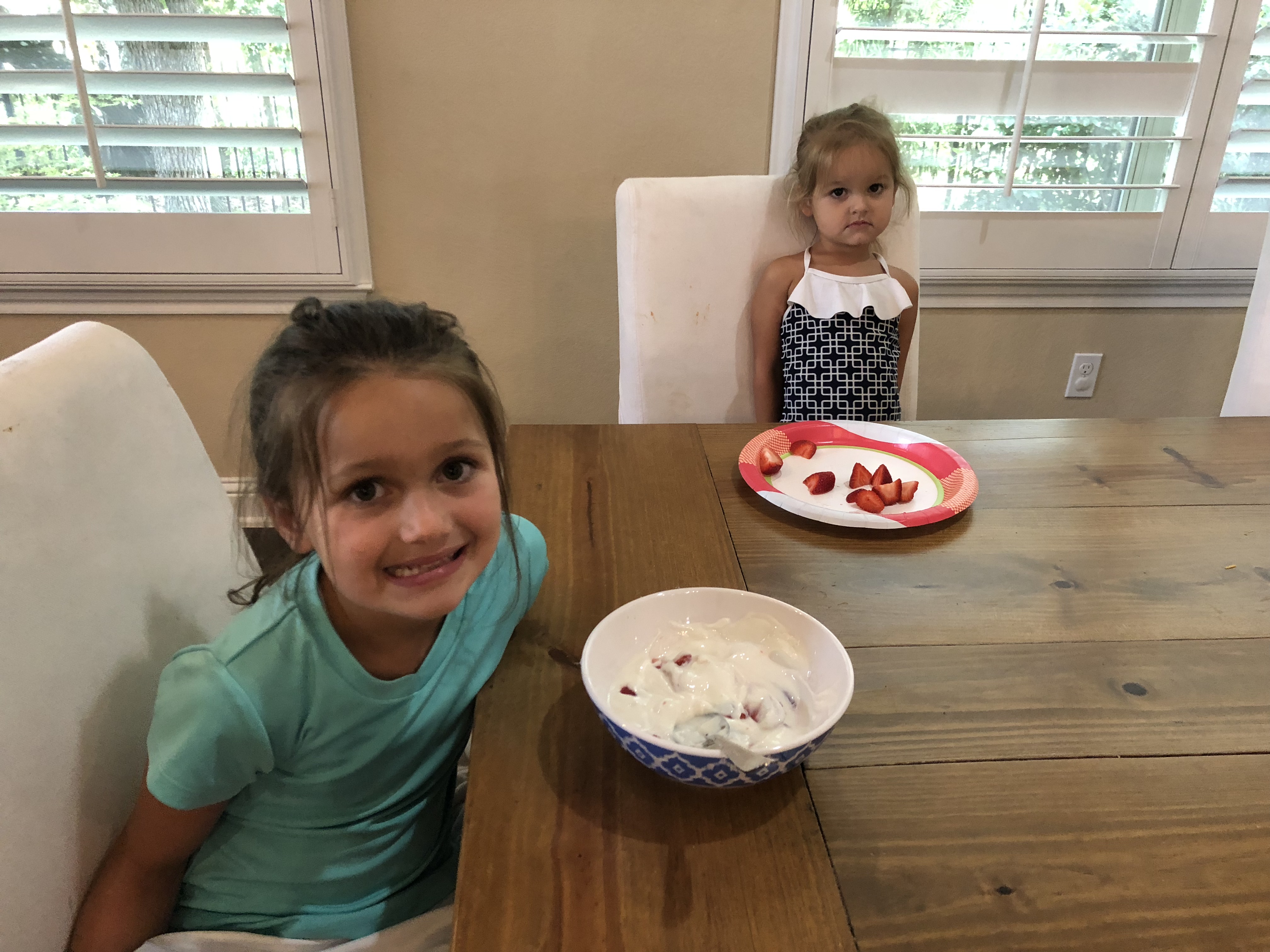 two young girls with yogurt and strawberries smiling
