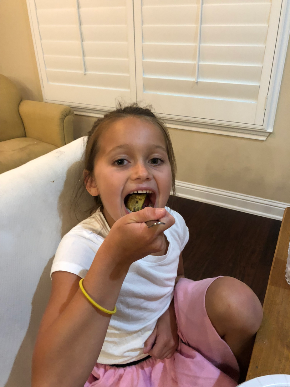 girl in pink skirt eating vegetable