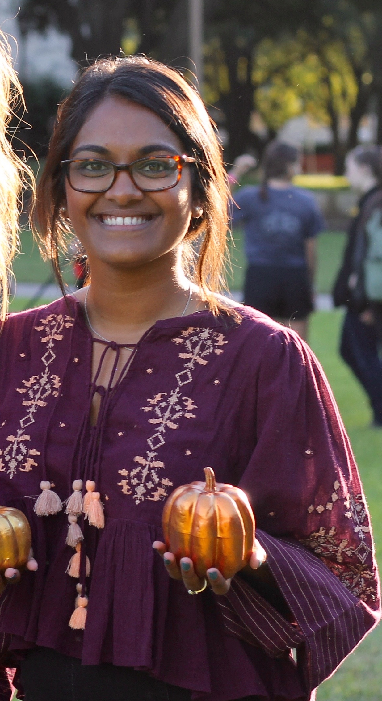 girl with glasses holding a small pumpkin